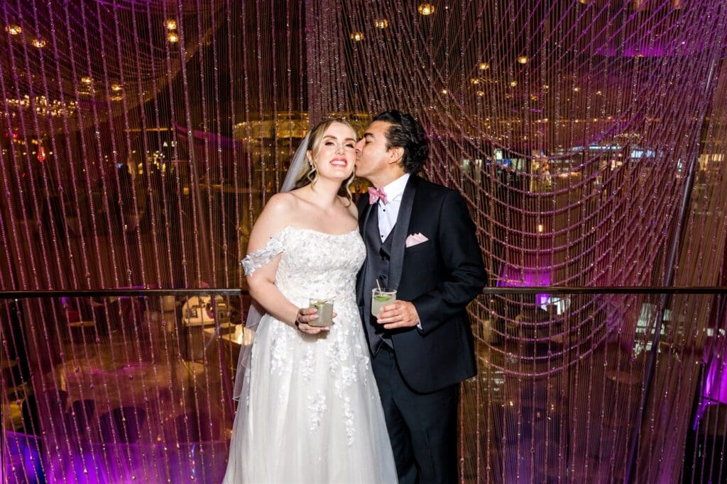 picture of the groom kissing the bride on the cheek 