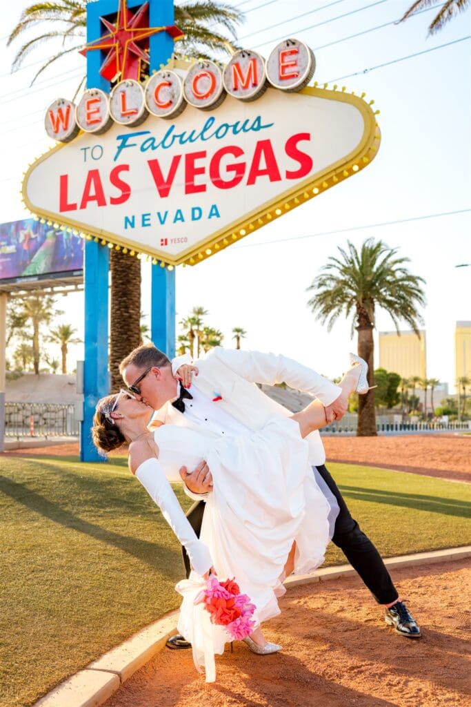 portrait of the newlyweds kissing in front of the las vegas sign 